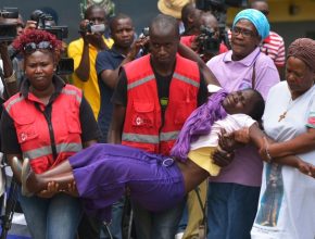 Membros da Cruz Vermelha carregam parente de um dos estudantes massacrados (Foto:Tony Karumba/AFP Photo) 