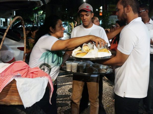 Jovens distribuem sopa e pão a moradores de rua em praça de Belém.