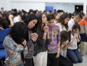 Adolescentes tornam o Congresso AdoleSer em momento de oração.