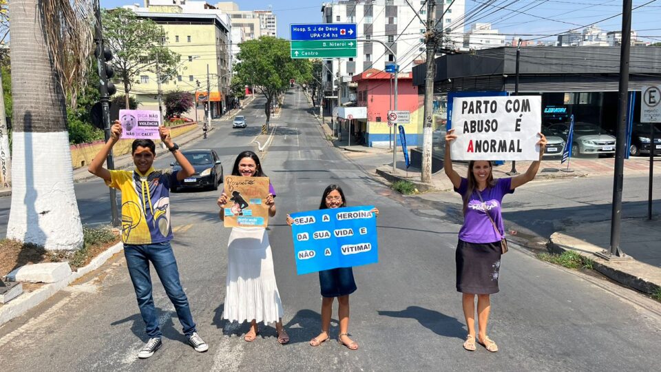 Pessoas no semáforo com placas sobre a campanha do Quebrando o Silêncio.