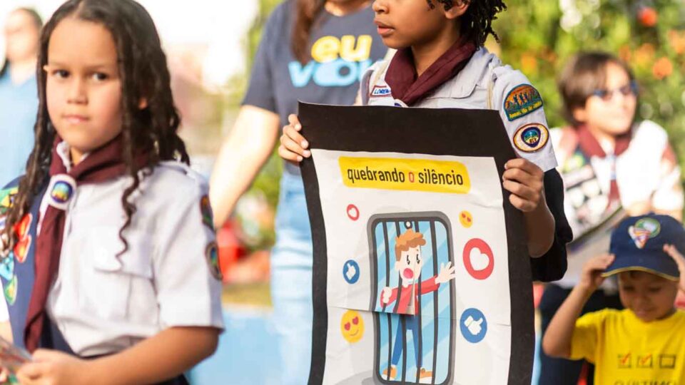 Criança segura faixa de conscientização durante a mobilização contra a violência digital em Caxias. (Foto: Filipe Braggio)