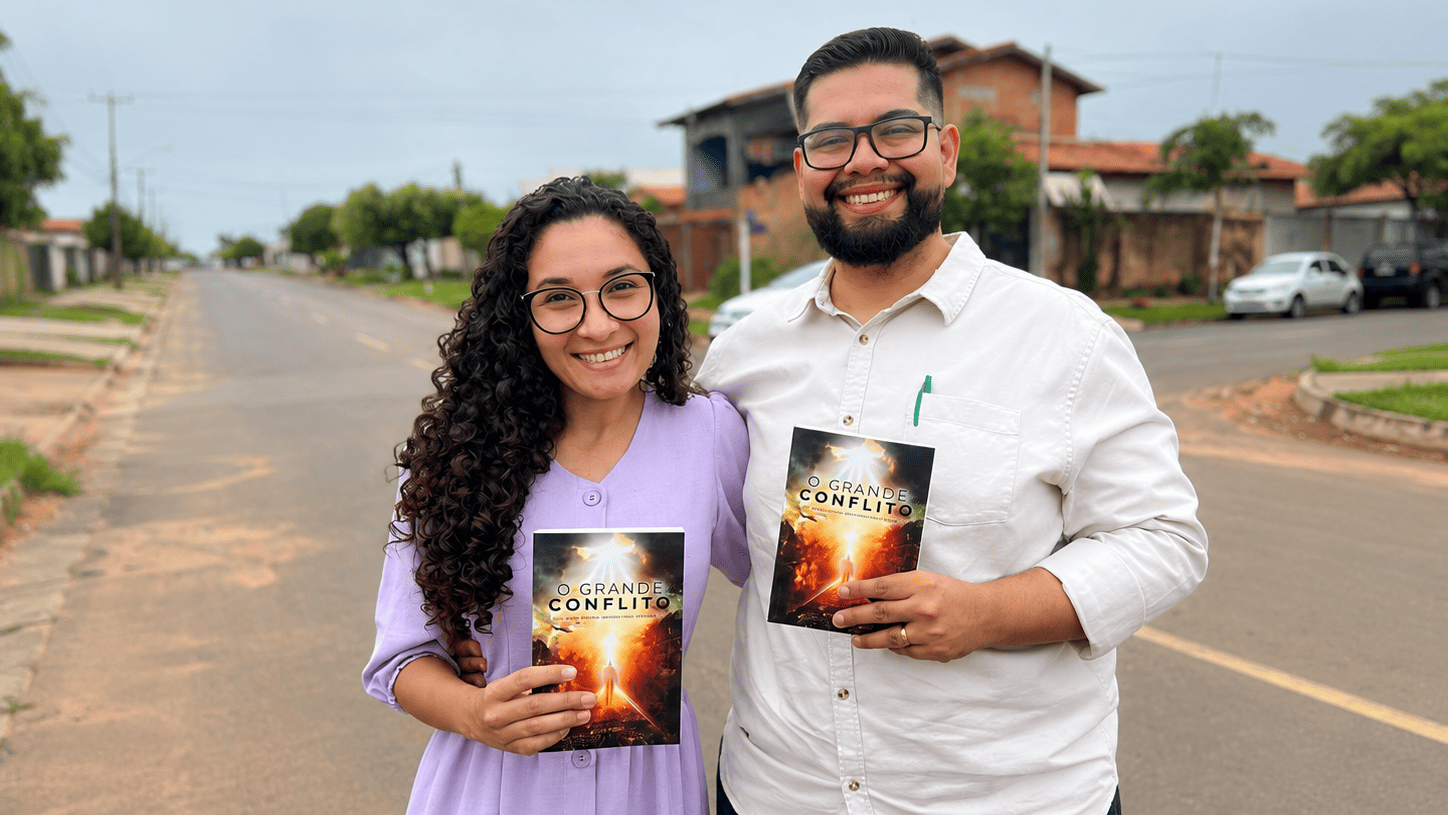 O casal abraçado na rua com livros missionários nas mãos.