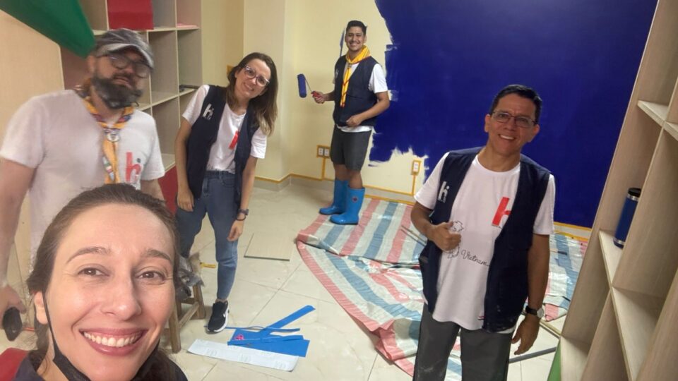Grupo de pessoas trabalhando voluntariamente no Vietnã e pintando paredes de um espaço para crianças
