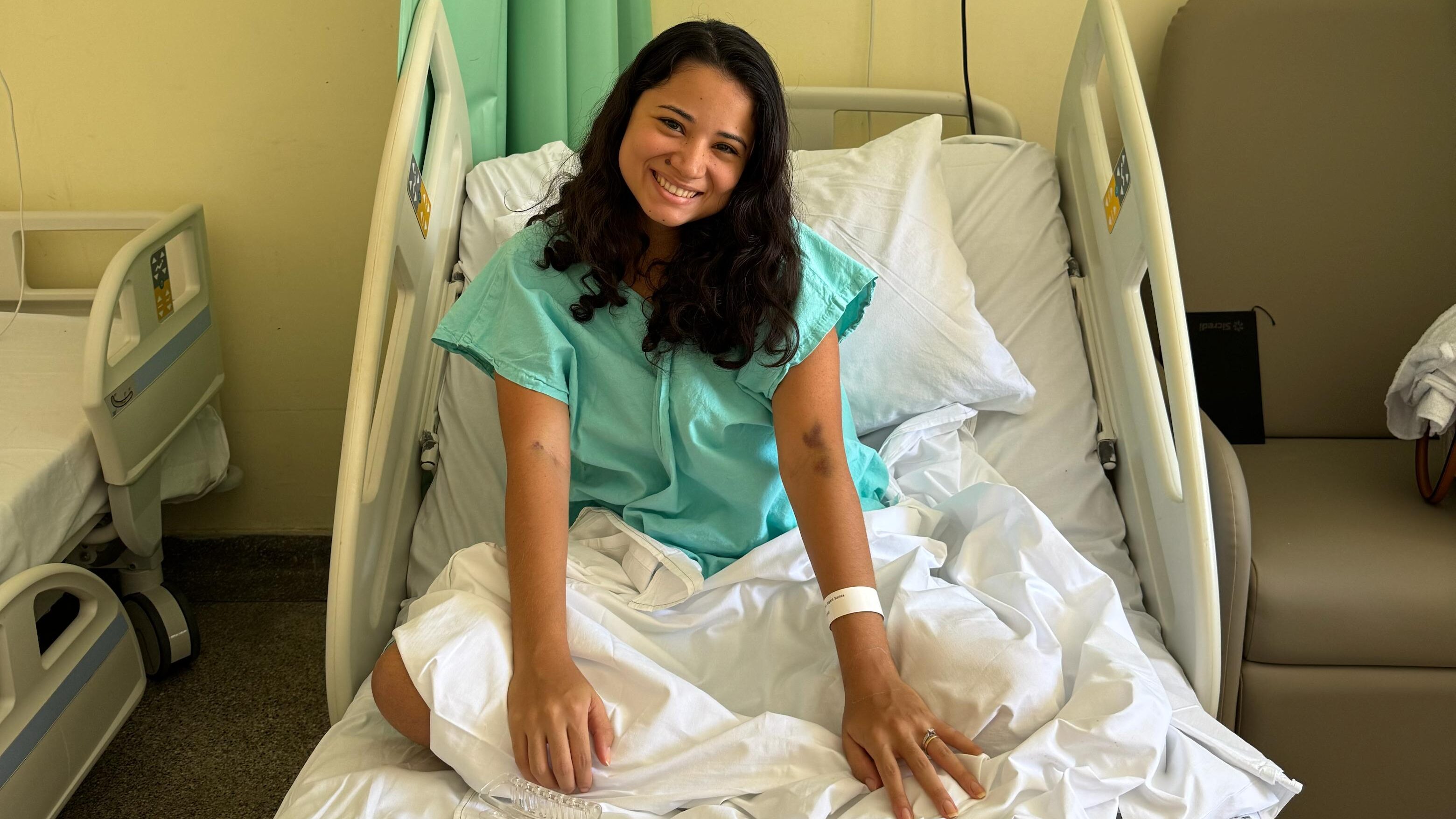 Clara sentada em uma maca de hospital