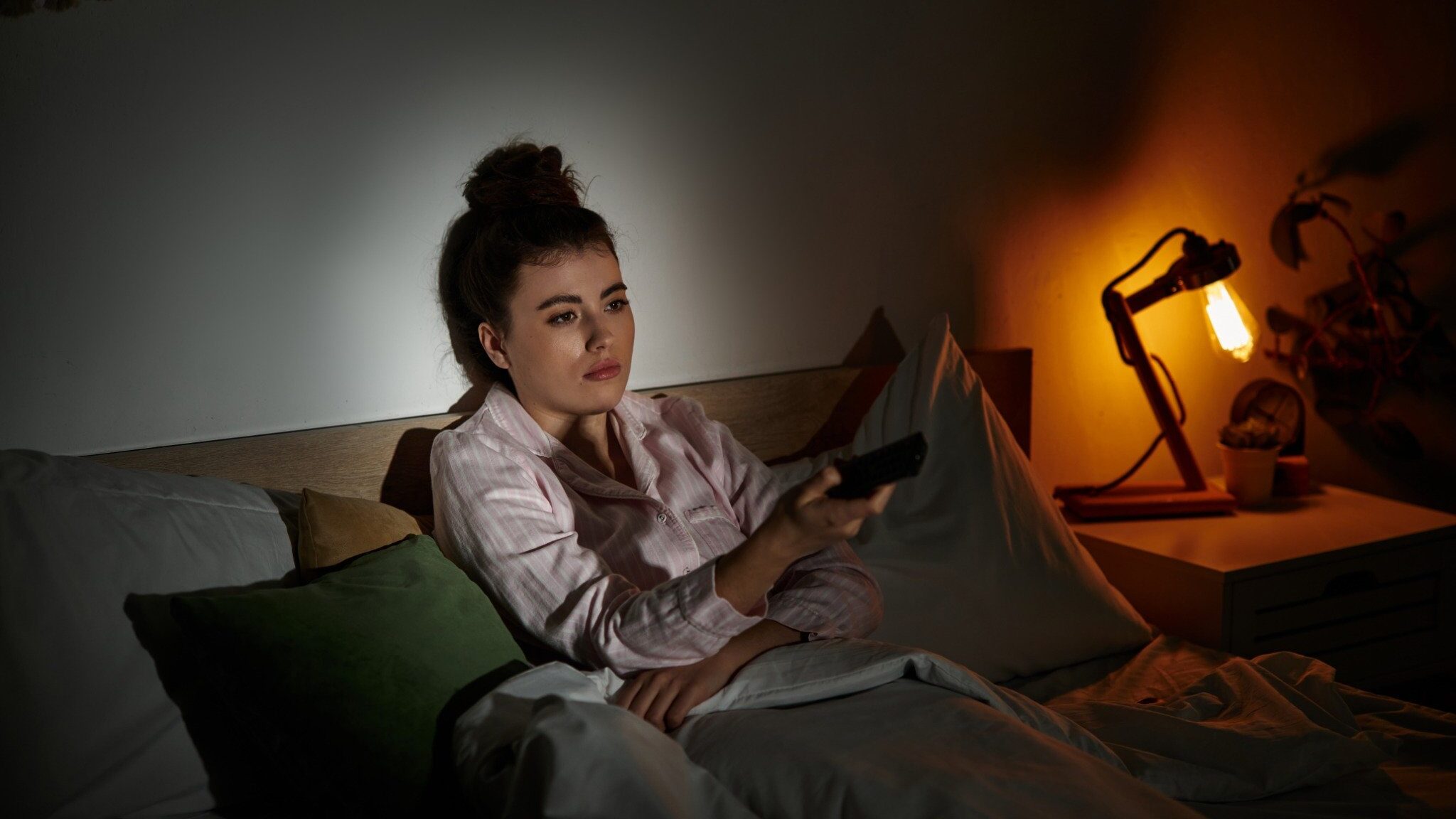 Menina deitada na cama assistindo Tv e preocupada com o mundo.