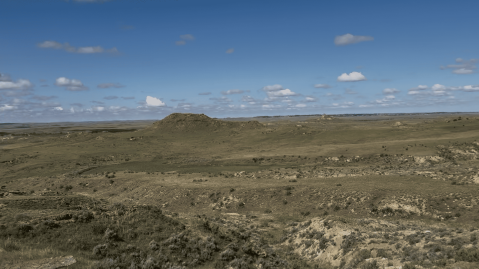 Paisagem do campo de pesquisa e ciência localizado em Wyoming, nos Estados Unidos. A vegetação é rasteira, levemente plana e o céu está azul.