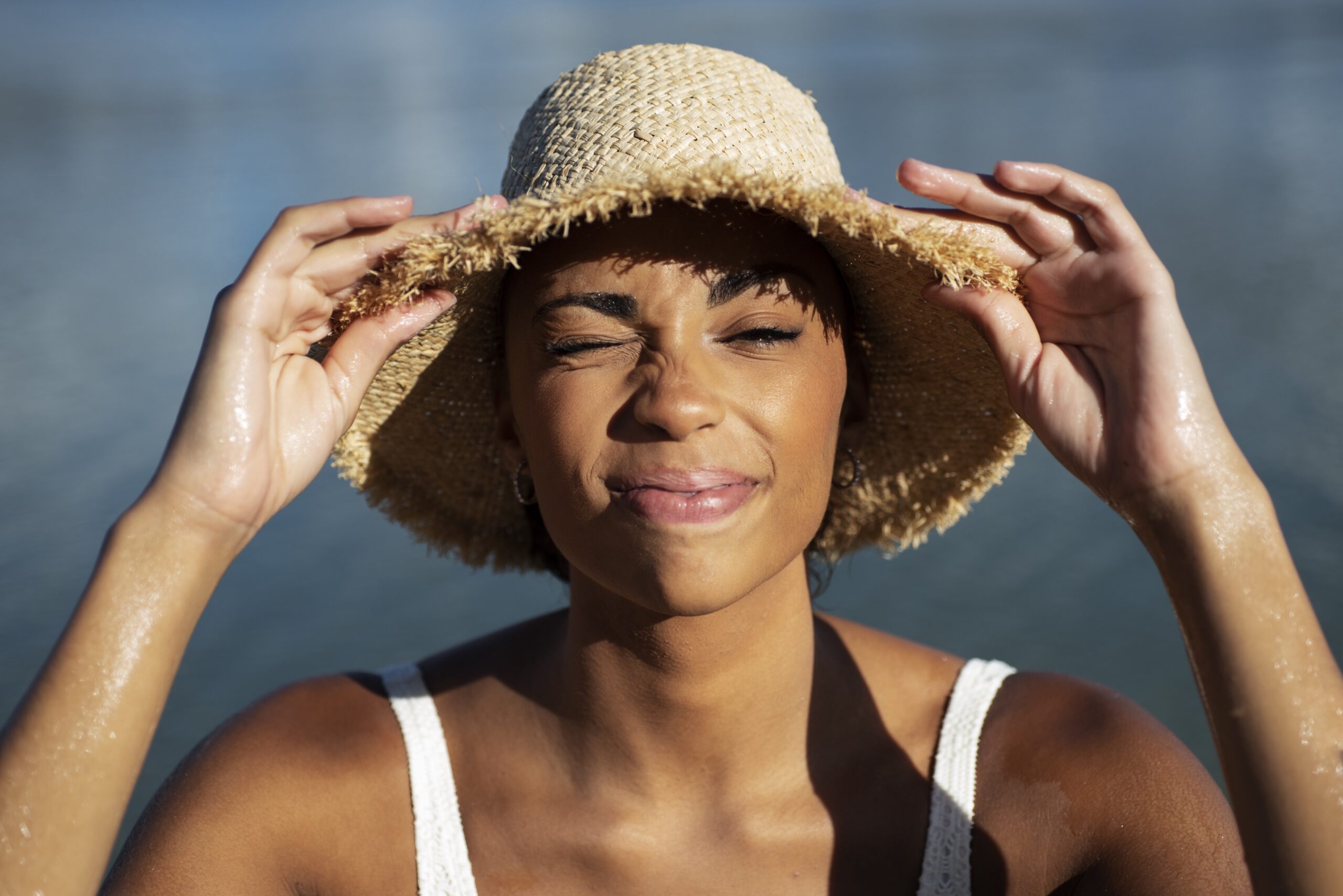 Mulher negra com chapéu com o sol batendo no rosto