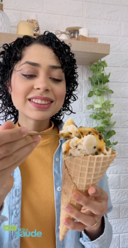 Mulher sorridente segurando um cone de sorvete vegano de maracujá.